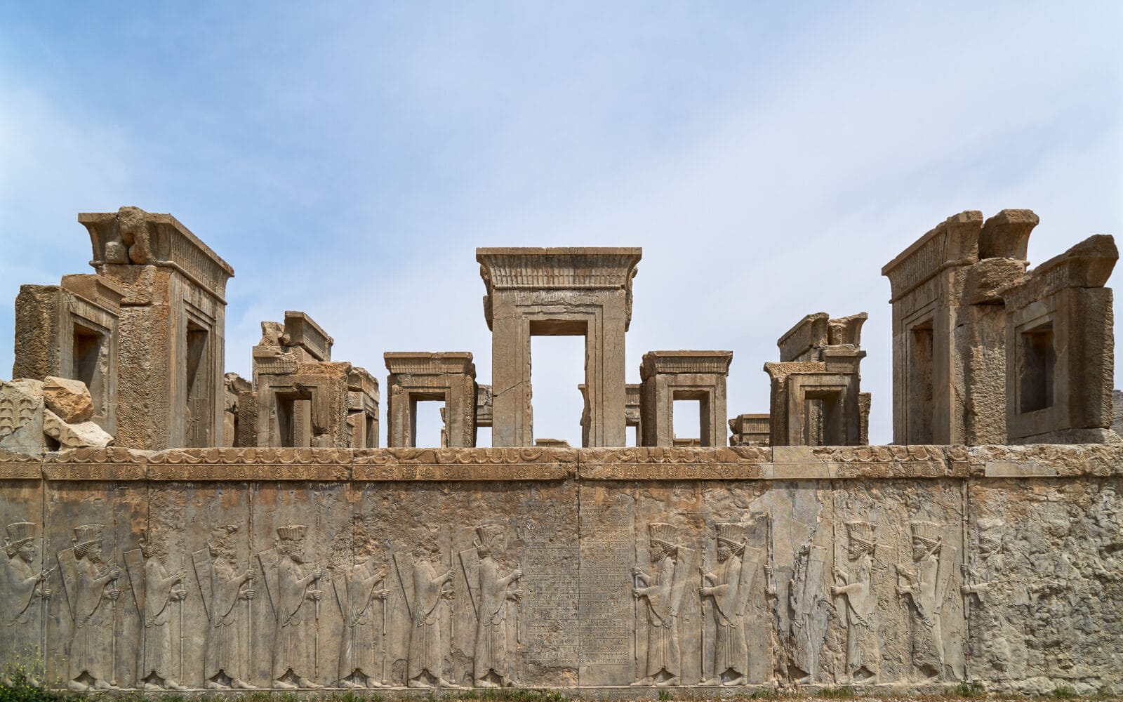 Perzische reliëfs van Persepolis tegen een felle hemel