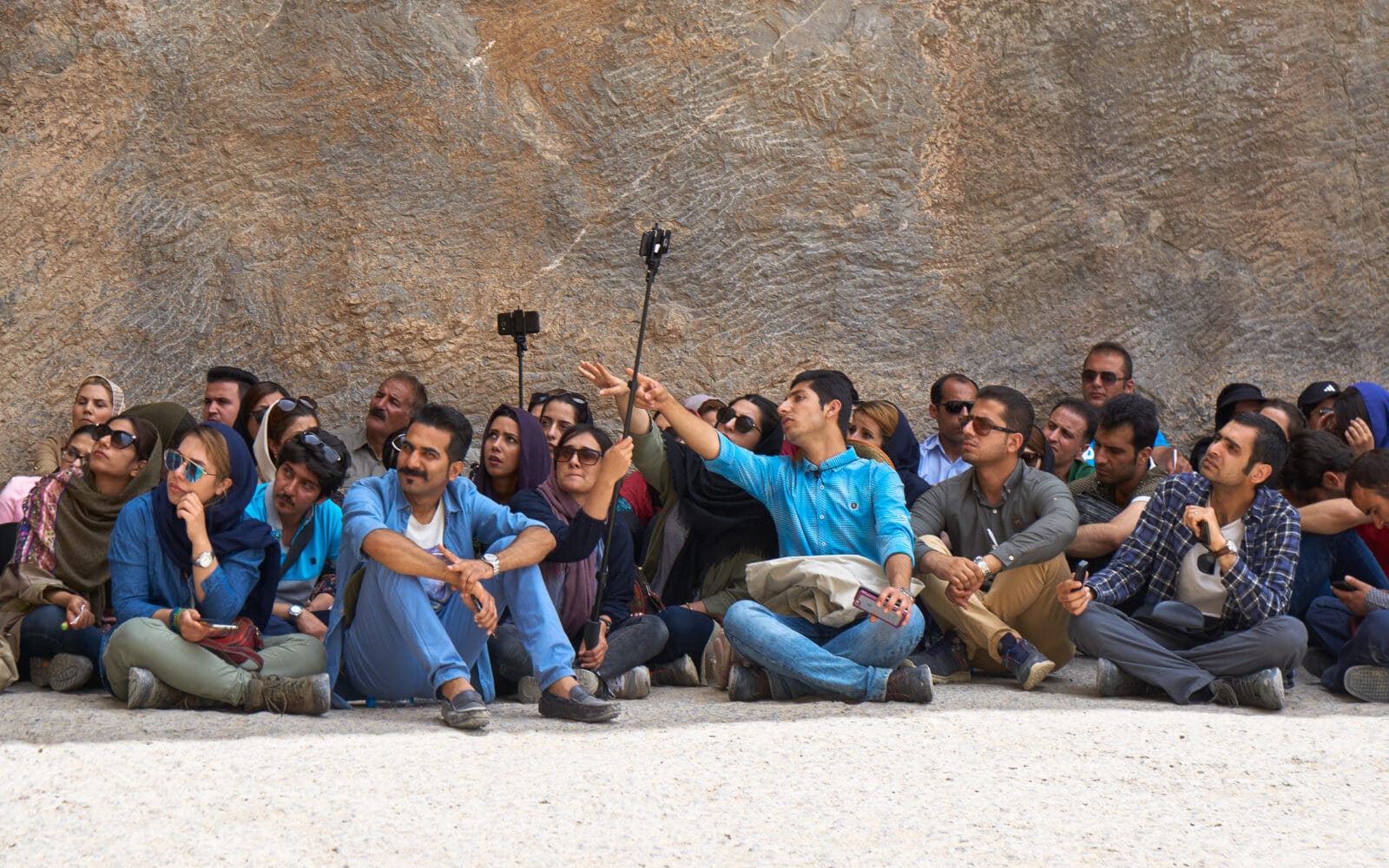 Bezoekers zitten op de grond te fotograferen in Persepolis