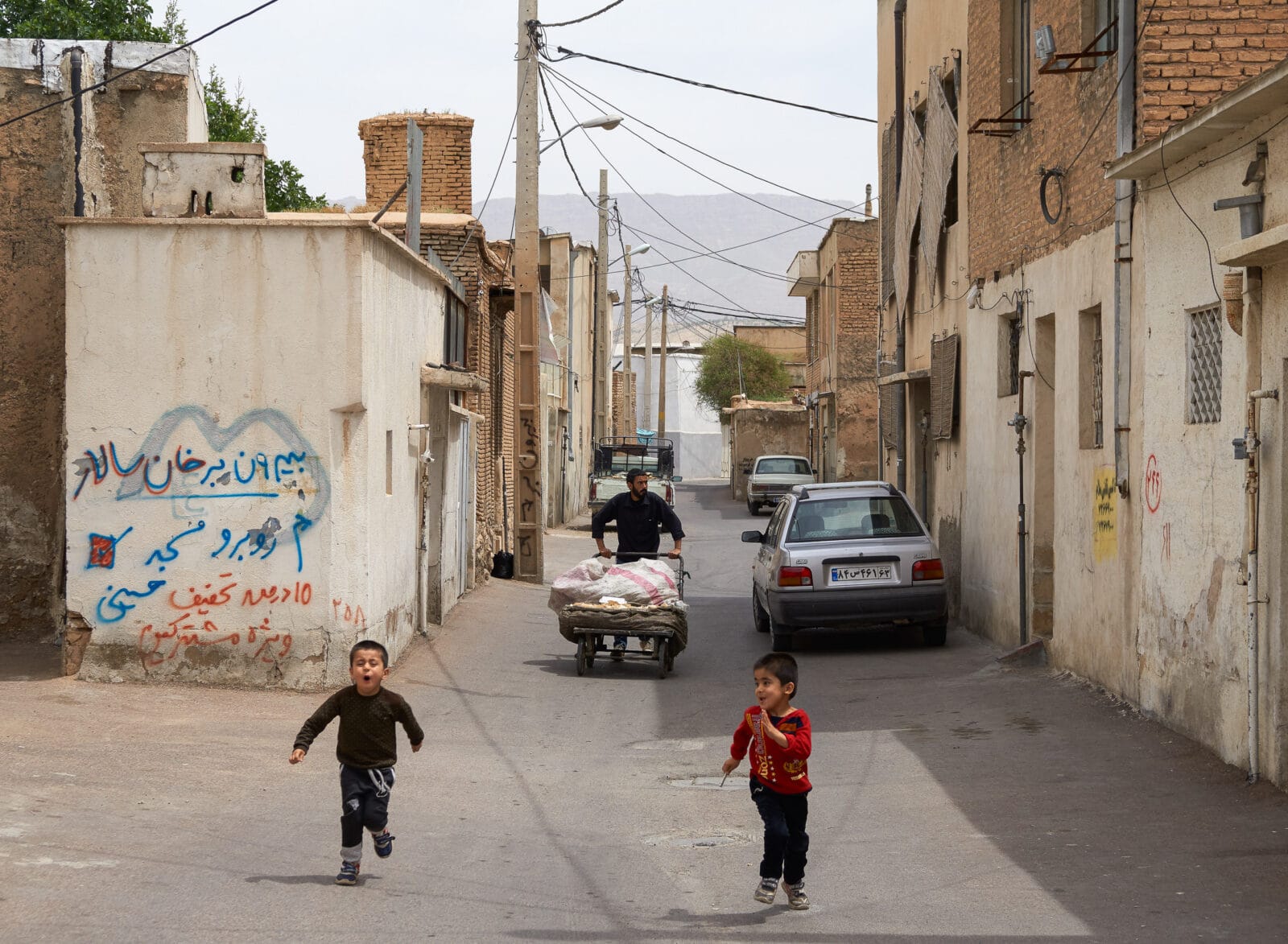 Kinderen spelen in een stoffige straat in Shiraz