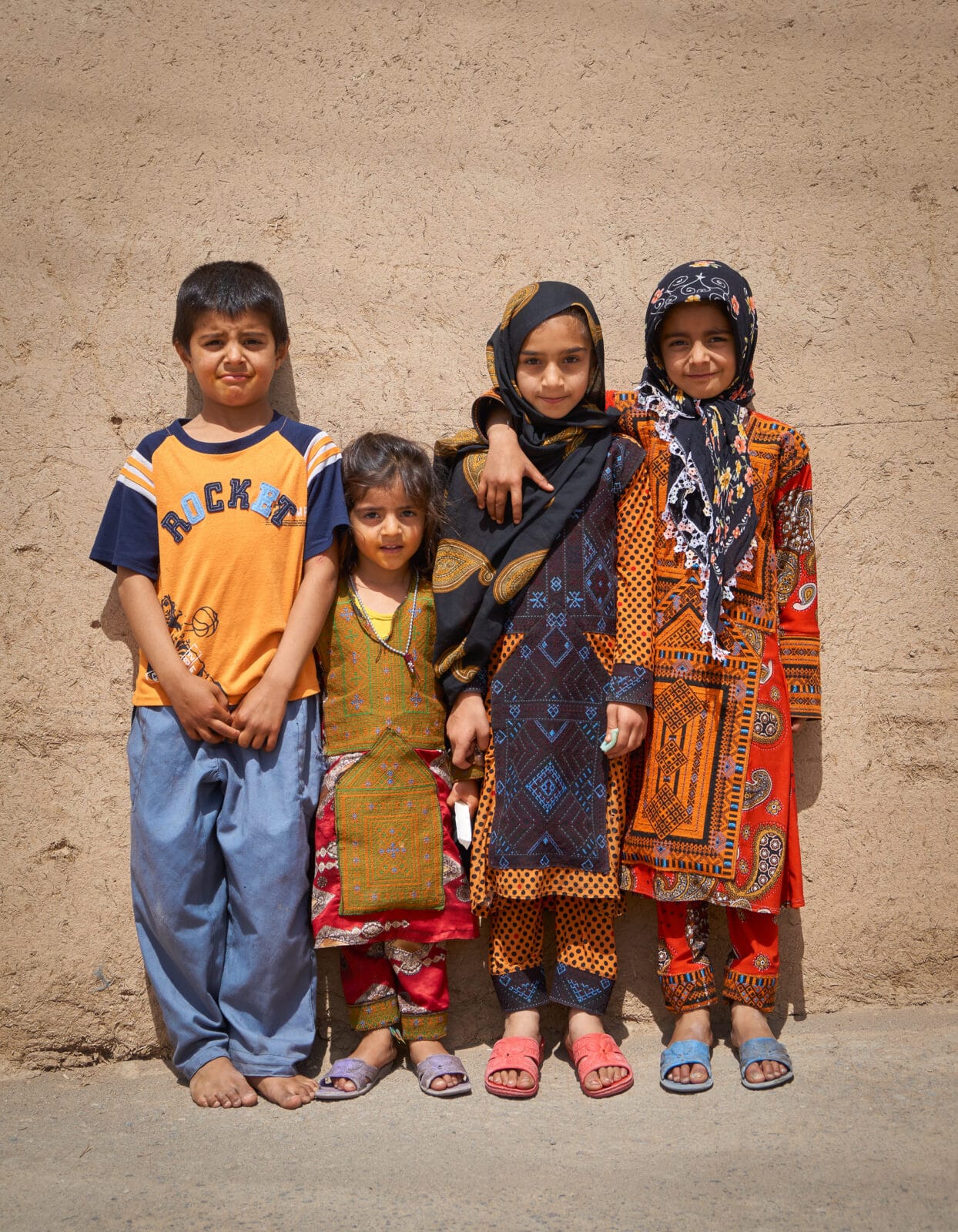 Vier kinderen tegen een lemen muur in Yazd