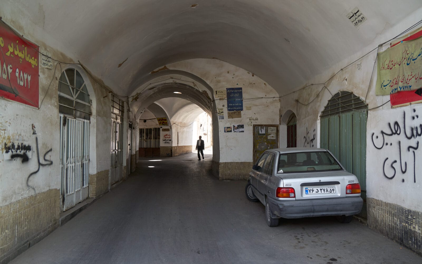 Man loopt door een overwelfde steeg in Yazd