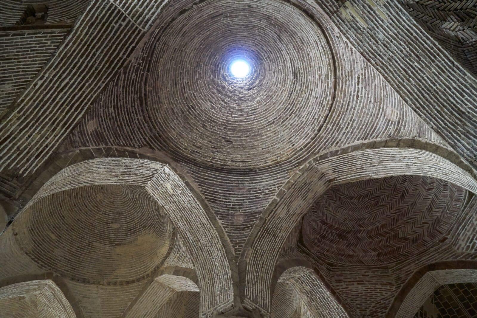 Licht valt door de bakstenen koepel van de Jameh-moskee in Isfahan
