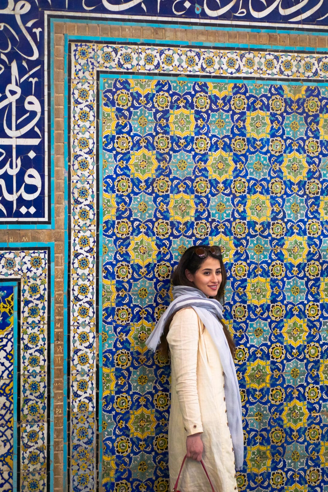 Vrouw lacht voor een mozaïekwand in Isfahan