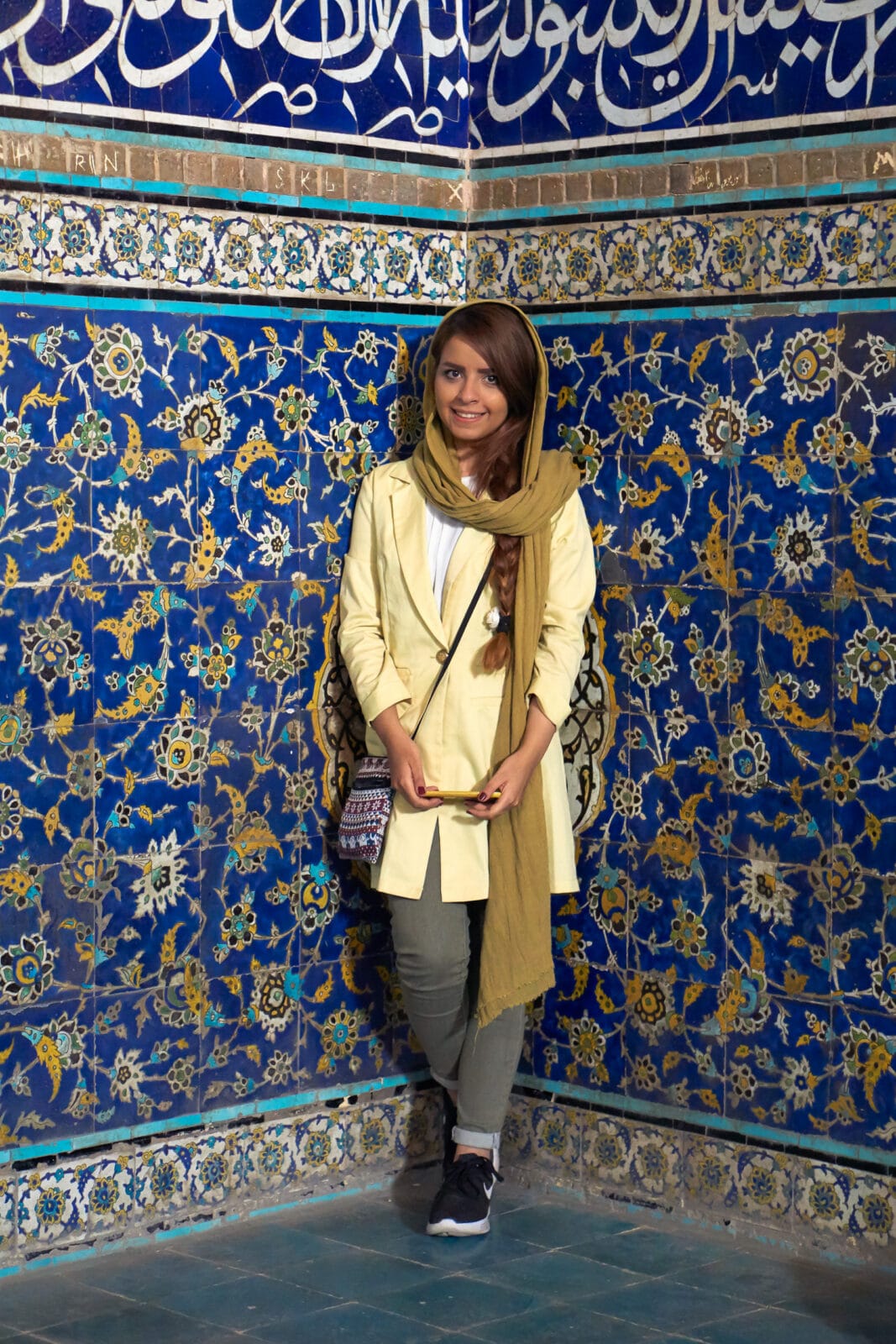 Jonge vrouw voor blauw tegelwerk op Naqsh-e Jahan in Isfahan