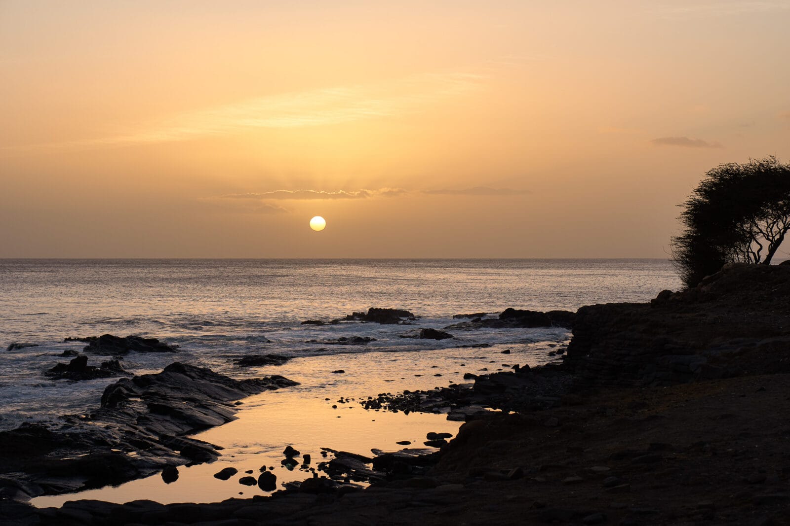 Zonsondergang boven de rotskust bij Quebra Canela in Praia