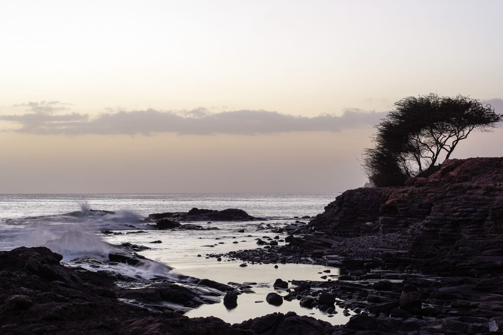 Golven op de rotskust van Praia bij zonsondergang
