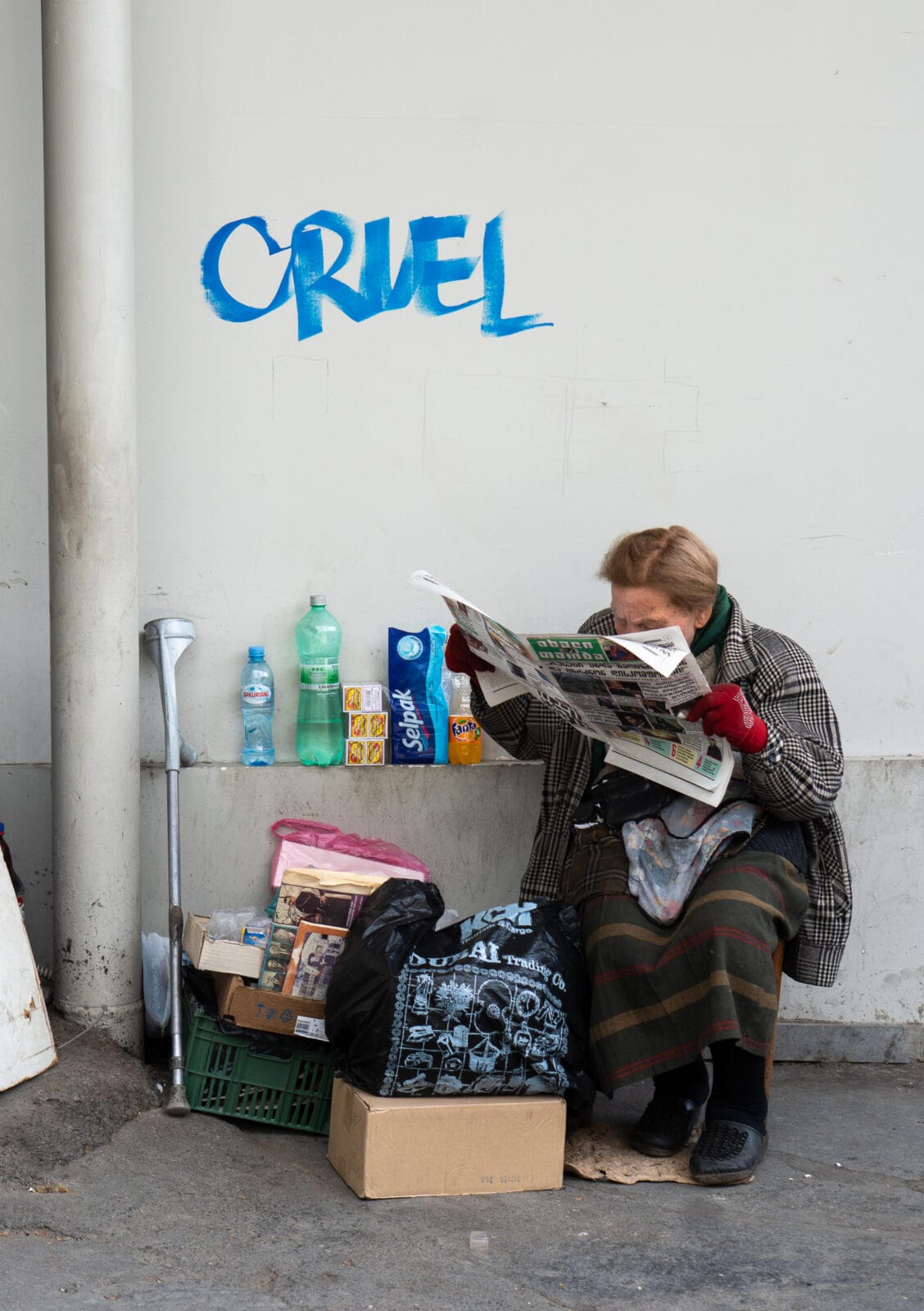 Vrouw leest de krant onder graffiti in Tbilisi