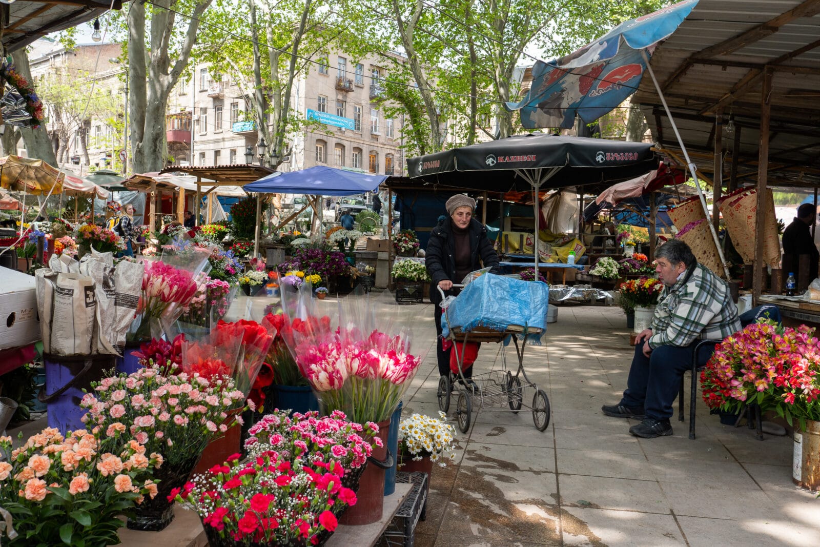 Vrouw duwt een kar door de bloemenmarkt van Tbilisi
