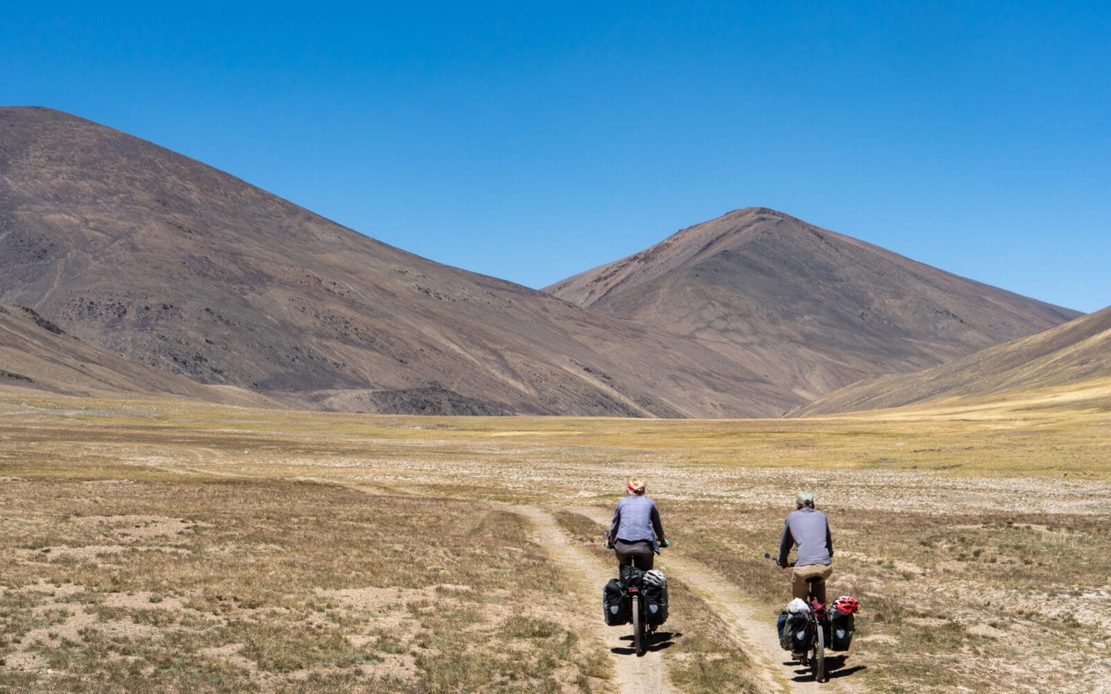 Twee fietsers in het weidse landschap van de oostelijke Pamir