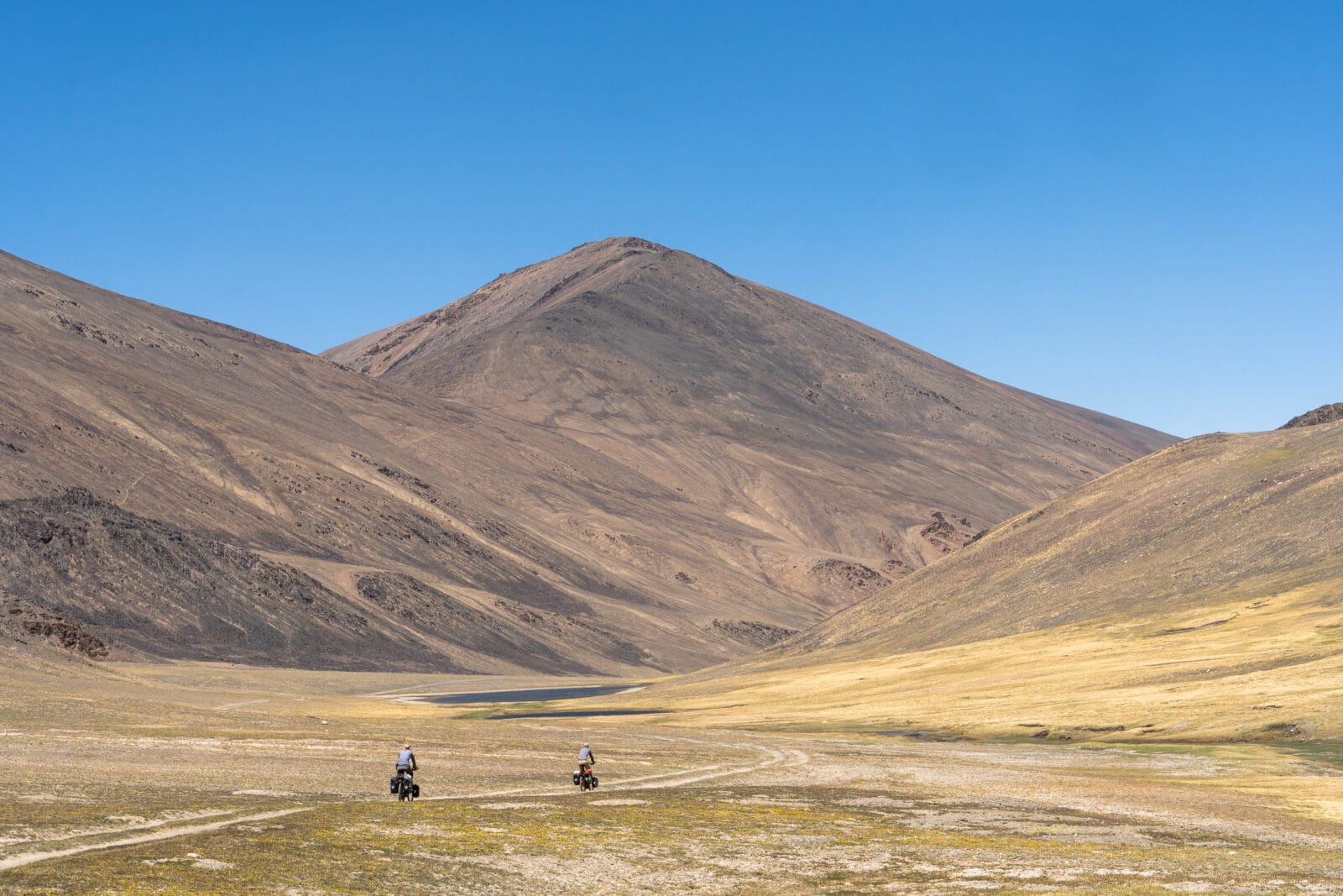 Twee fietsers door het brede dal van de oostelijke Pamir