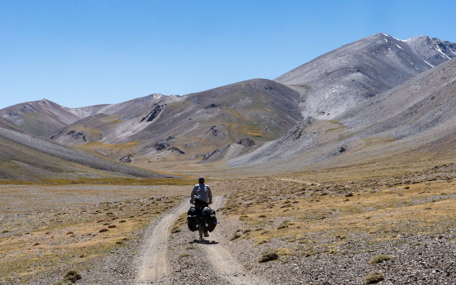 Eenzame fietser in het weidse landschap van de oostelijke Pamir