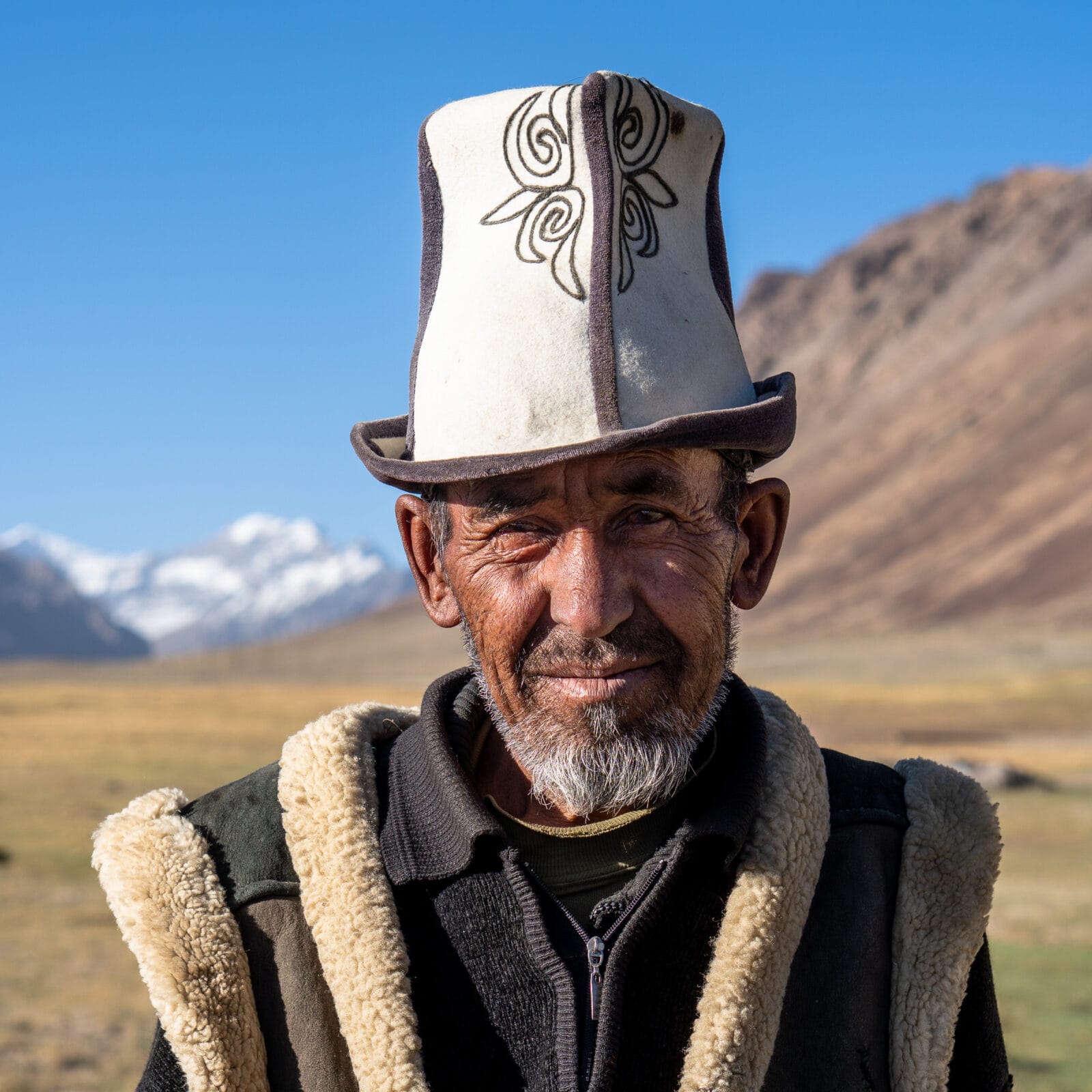 Man met traditionele muts en winterjas op de Pamir-hoogvlakte