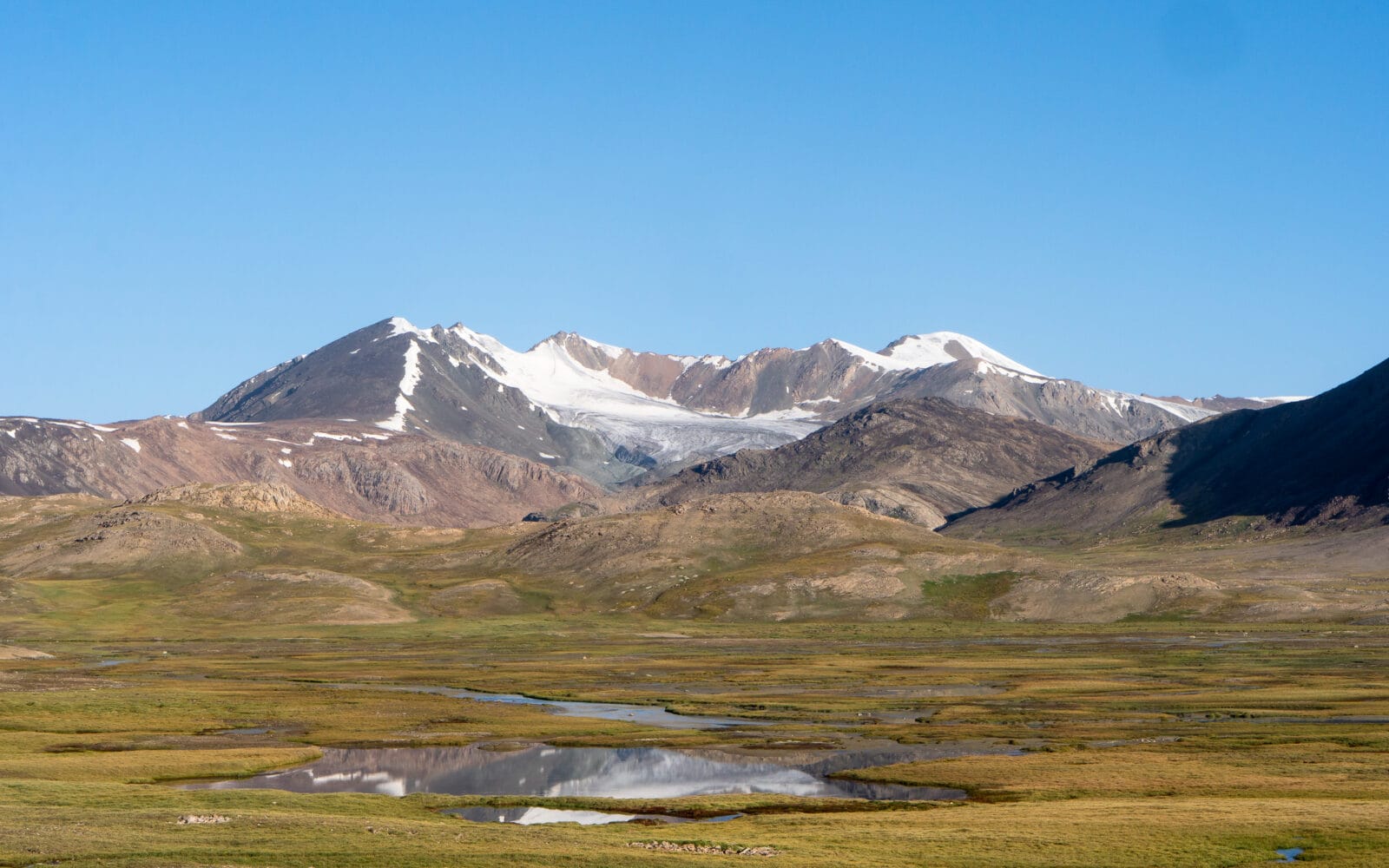 Weids berglandschap met rivier en besneeuwde toppen op de Arabel-hoogvlakte