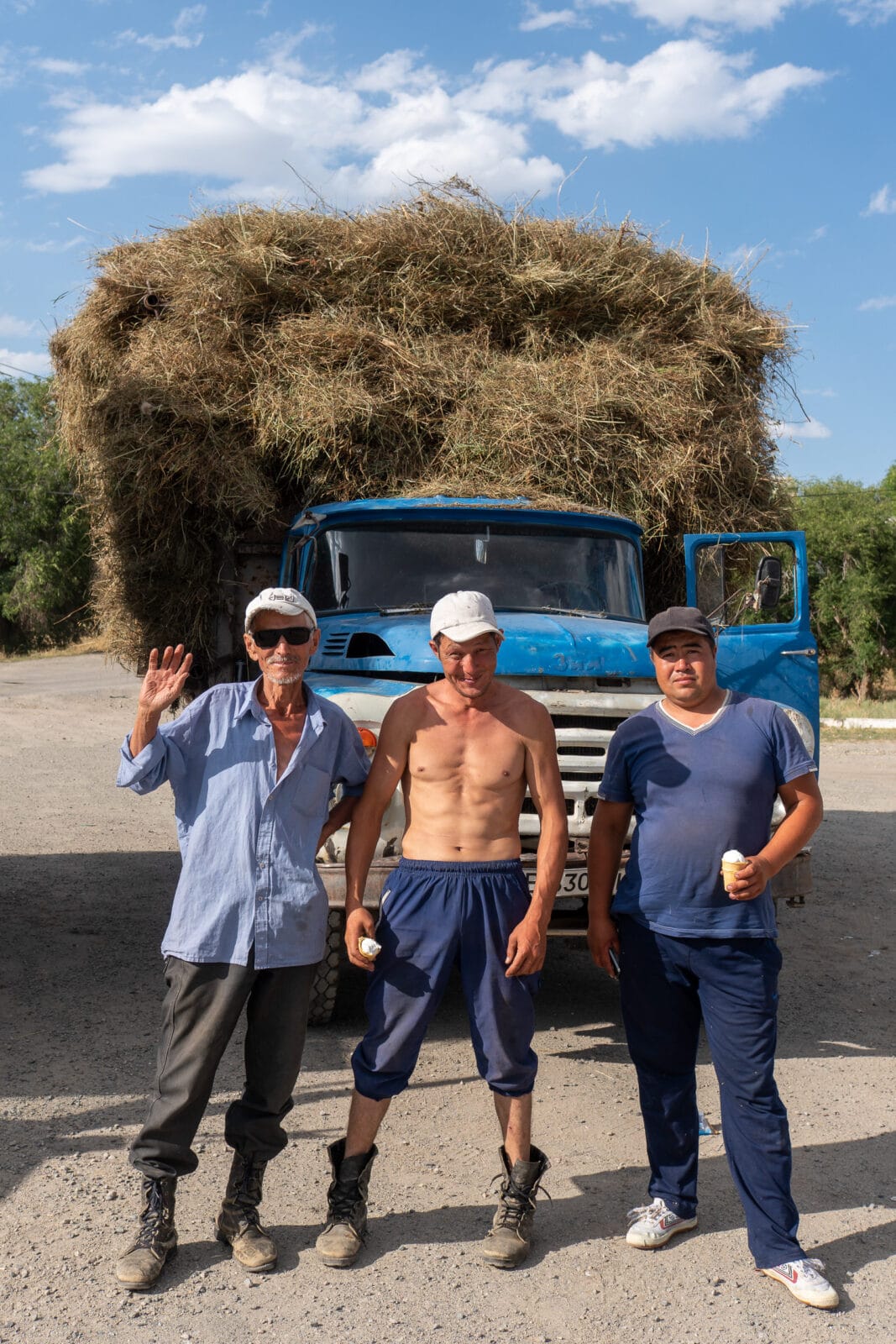 Drie mannen bij een hoog opgeladen hooiwagen bij Kapal
