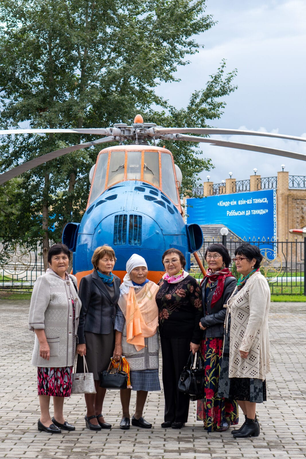 Zes vrouwen poseren voor een blauwe helikopter in Öskemen