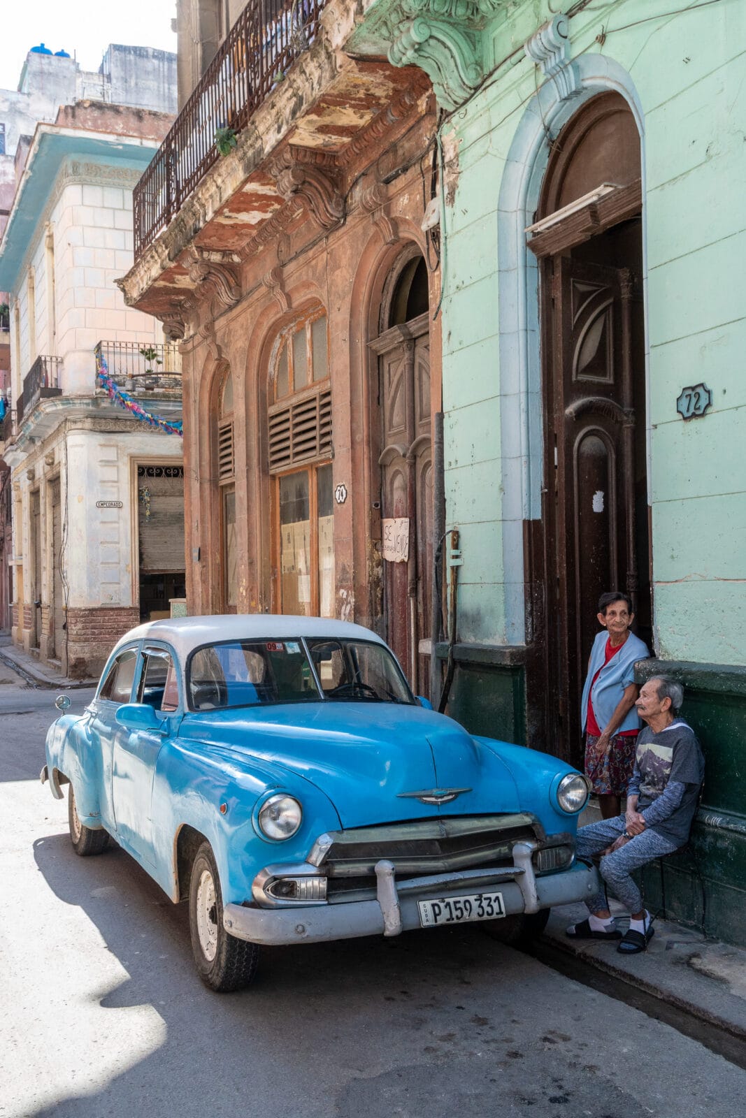 Blauwe oldtimer voor een verweerde gevel in Centro Habana