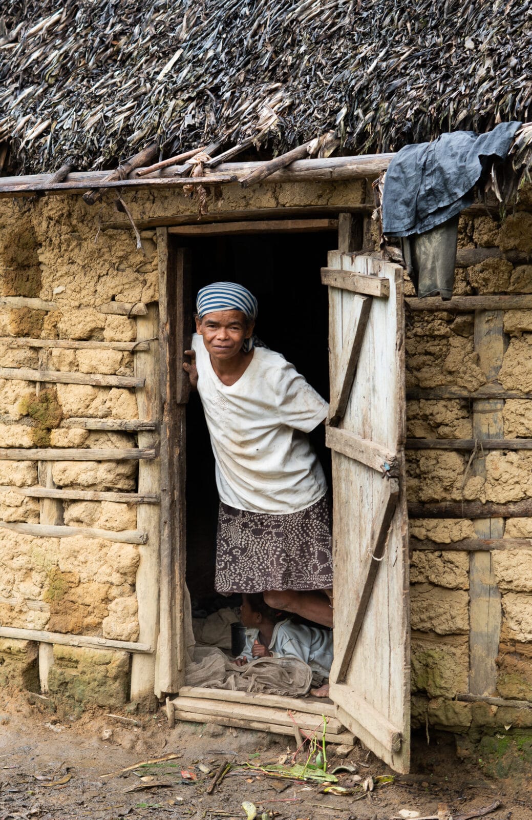 Vrouw in de deuropening van een houten huis bij Ranomafana
