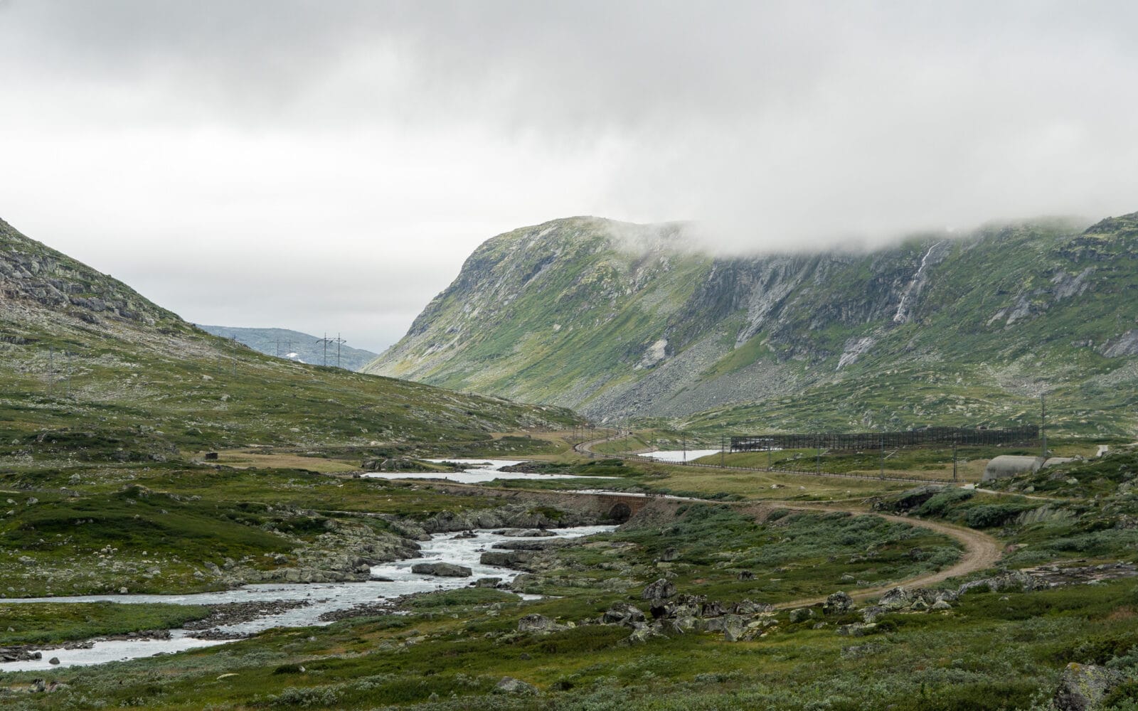 Mistige bergen en een kronkelend rivierdal langs de Rallarvegen op de Hardangervidda