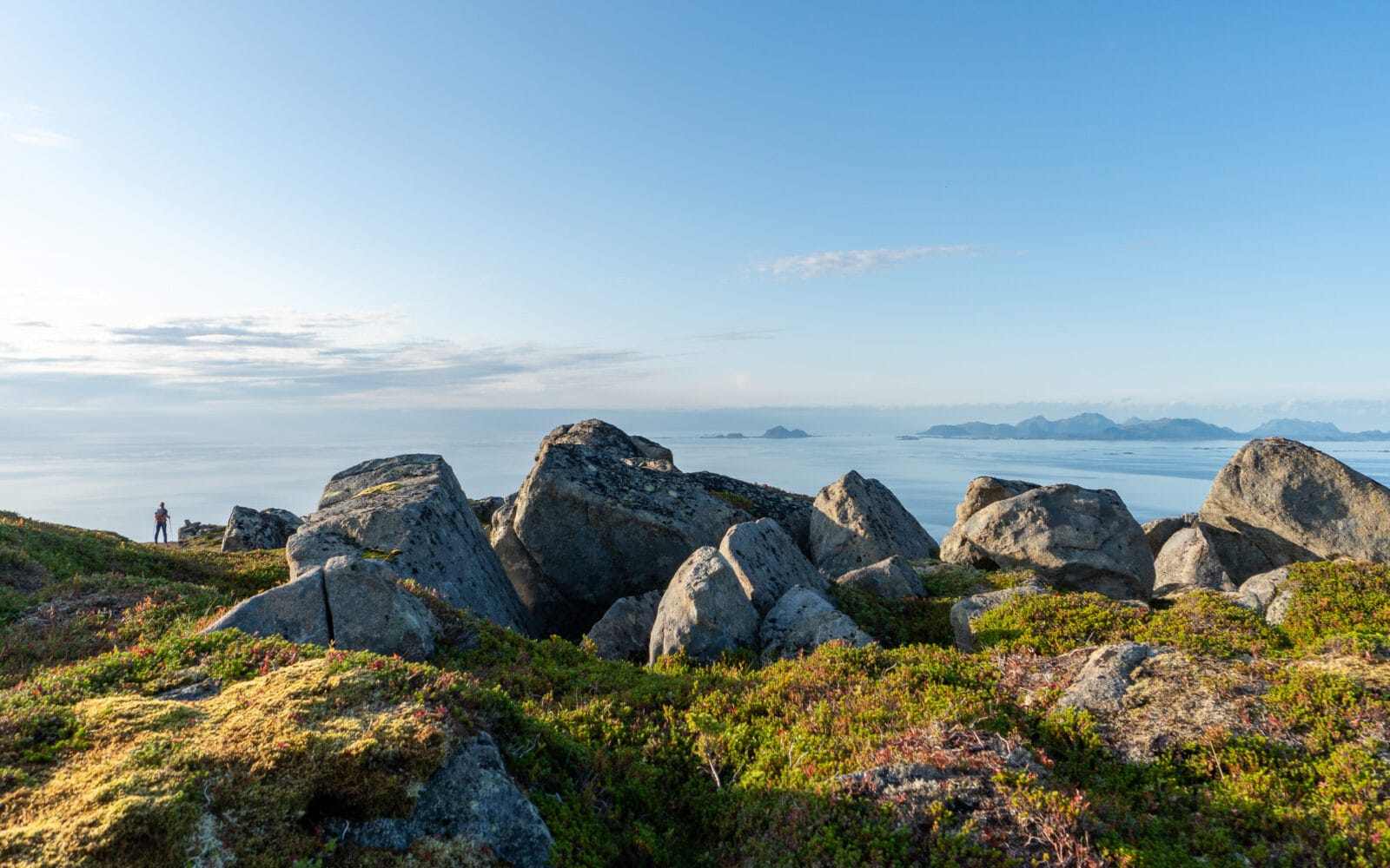 Een wandelaar kijkt vanaf de top uit over de oceaan bij Laukvik op Austvågøya