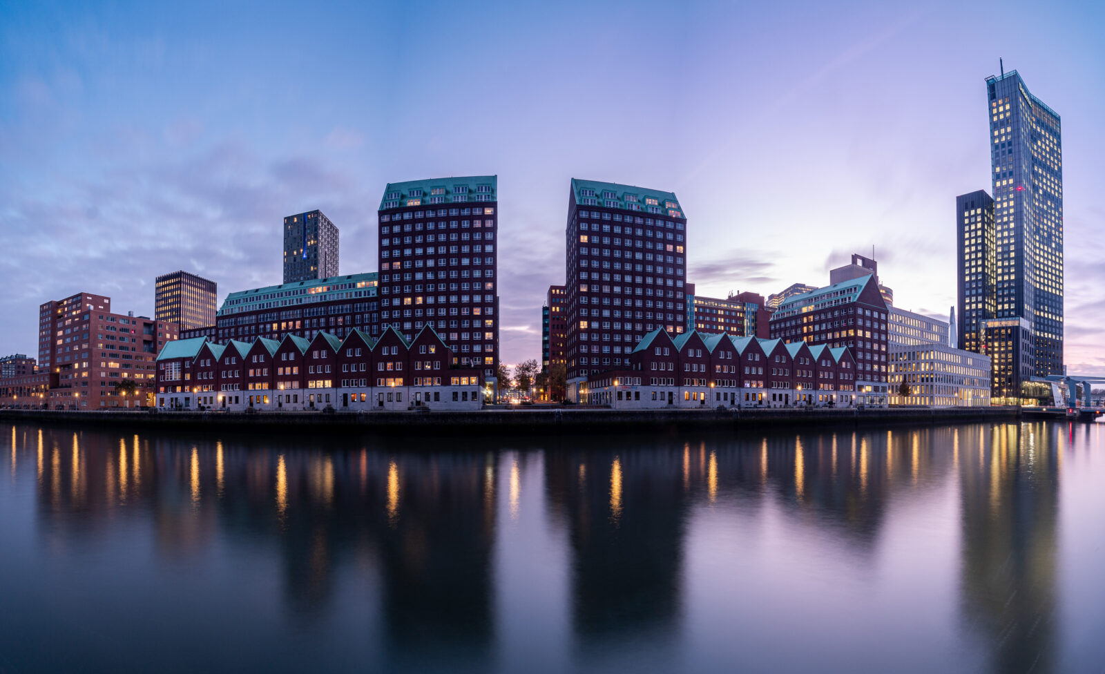 De skyline van Rotterdam in kalm water, schemering