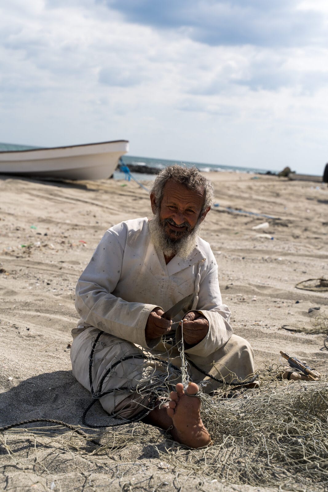 Visser herstelt zijn net op het strand van Masirah