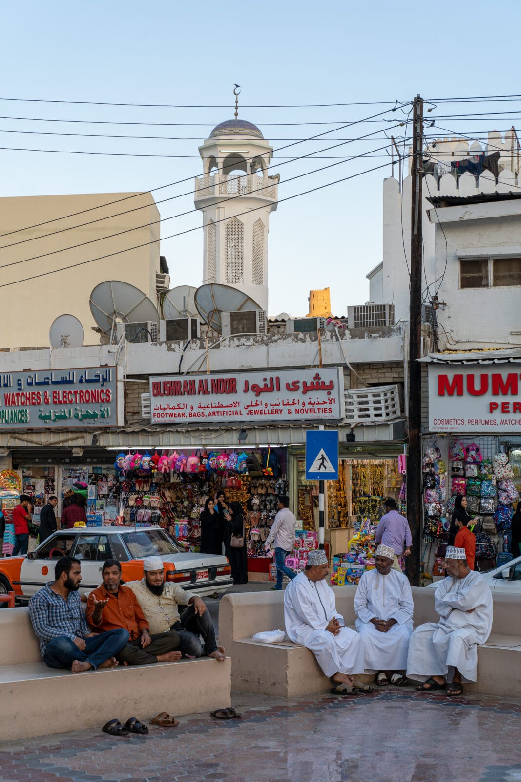 Mannen bij de winkels met de moskee erachter in Muttrah, Muscat