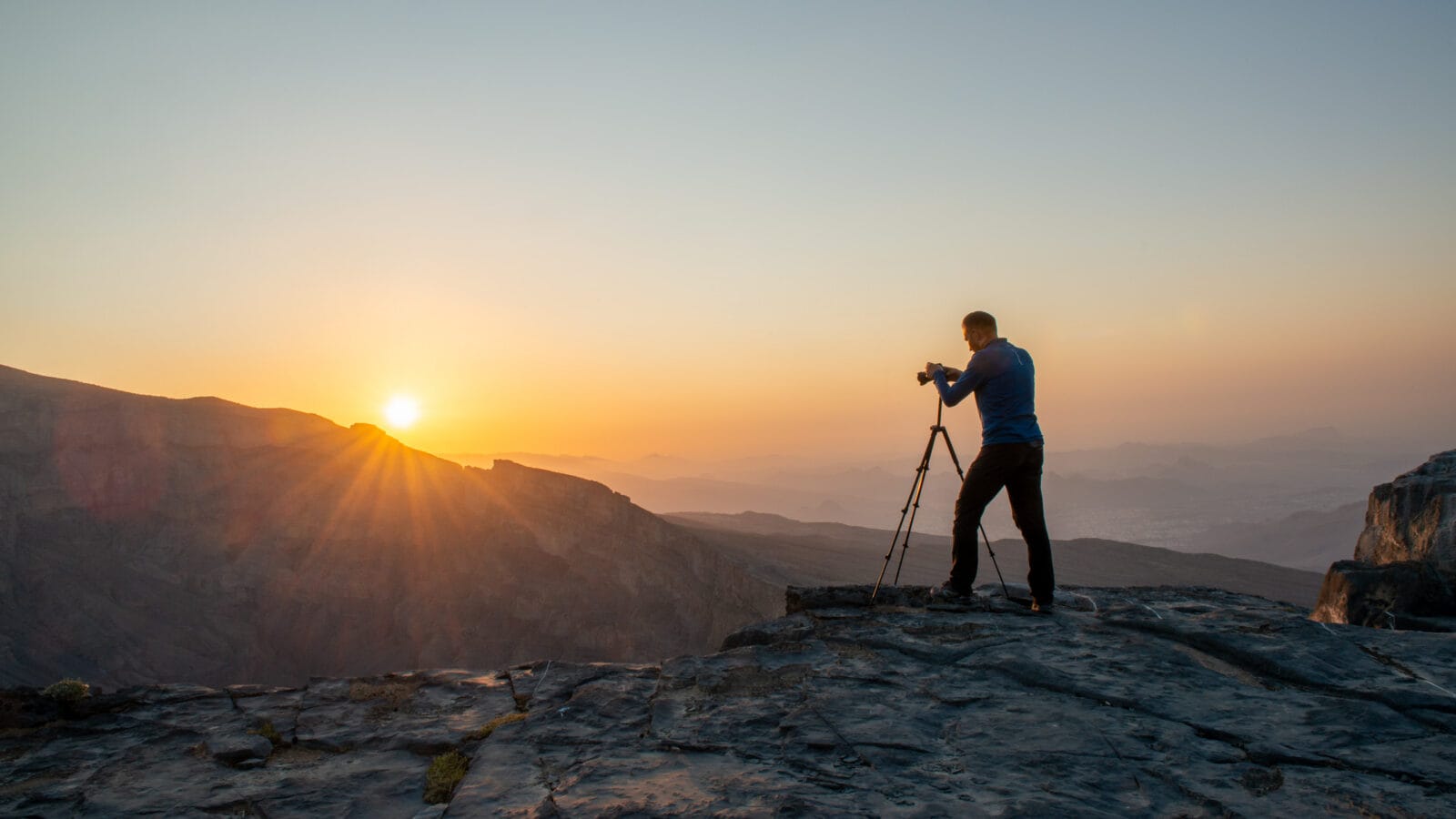 Fotograaf bij zonsopkomst boven de nevelige bergen op Jebel Shams