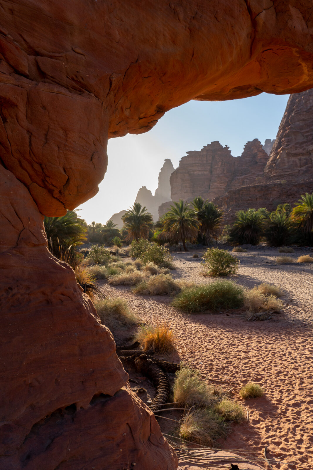 Oase gezien door een rotsboog in Wadi Disah