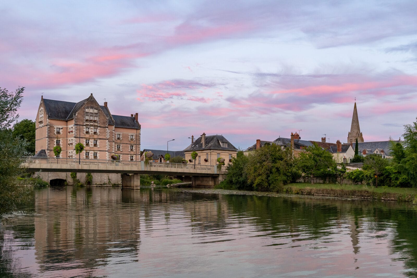 Roze lucht boven de rivier en de oude huizen van Veigné