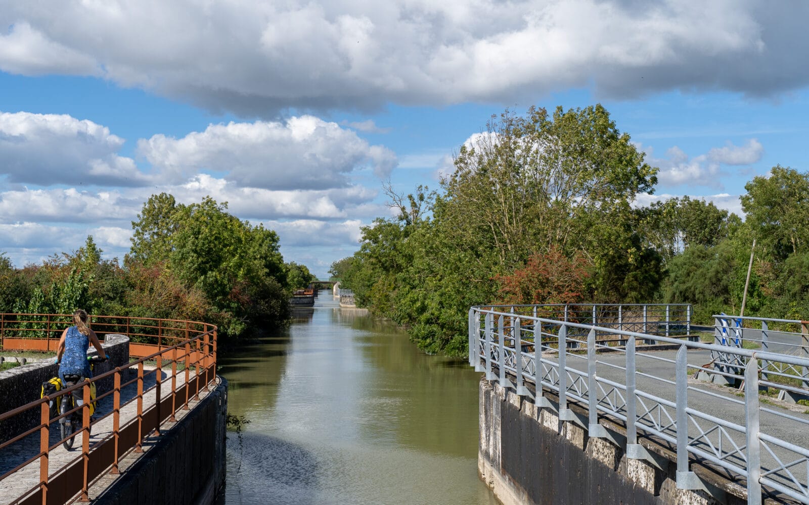Fietsster langs het kanaal onder een wolkenlucht bij Marans