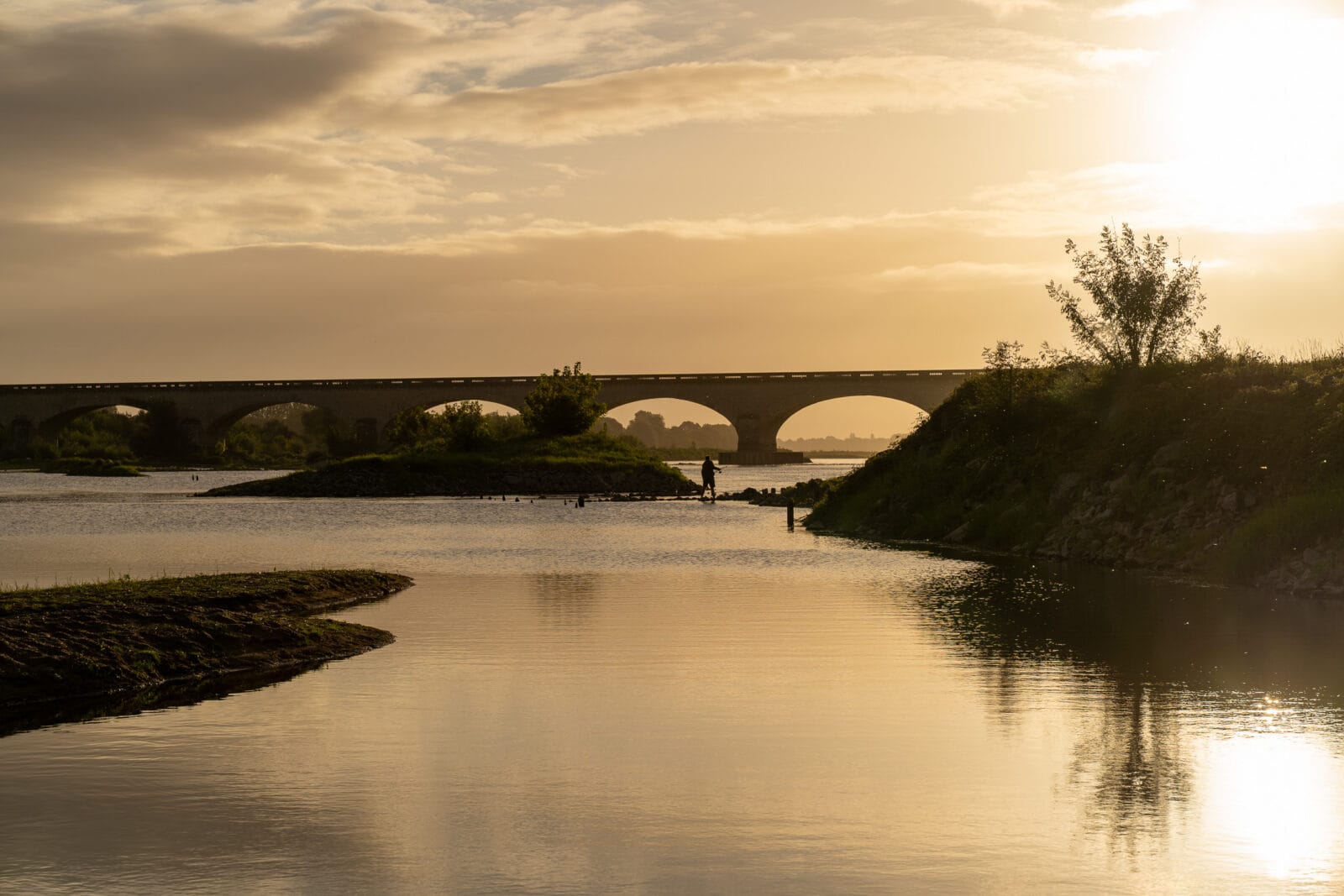 Brug en wandelaar in het avondlicht aan de Loire bij Chalonnes-sur-Loire