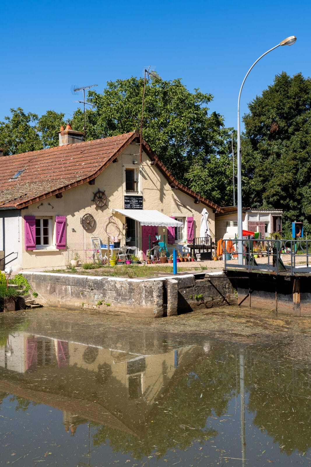 Kanaalhuis met roze luiken weerspiegeld in het water bij Fleury-sur-Loire