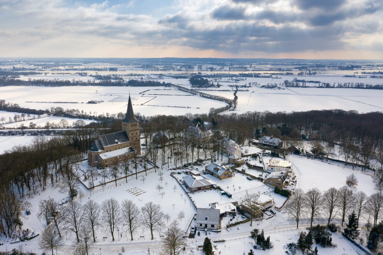 Besneeuwd Elten met de kerk tussen kale bomen, van boven