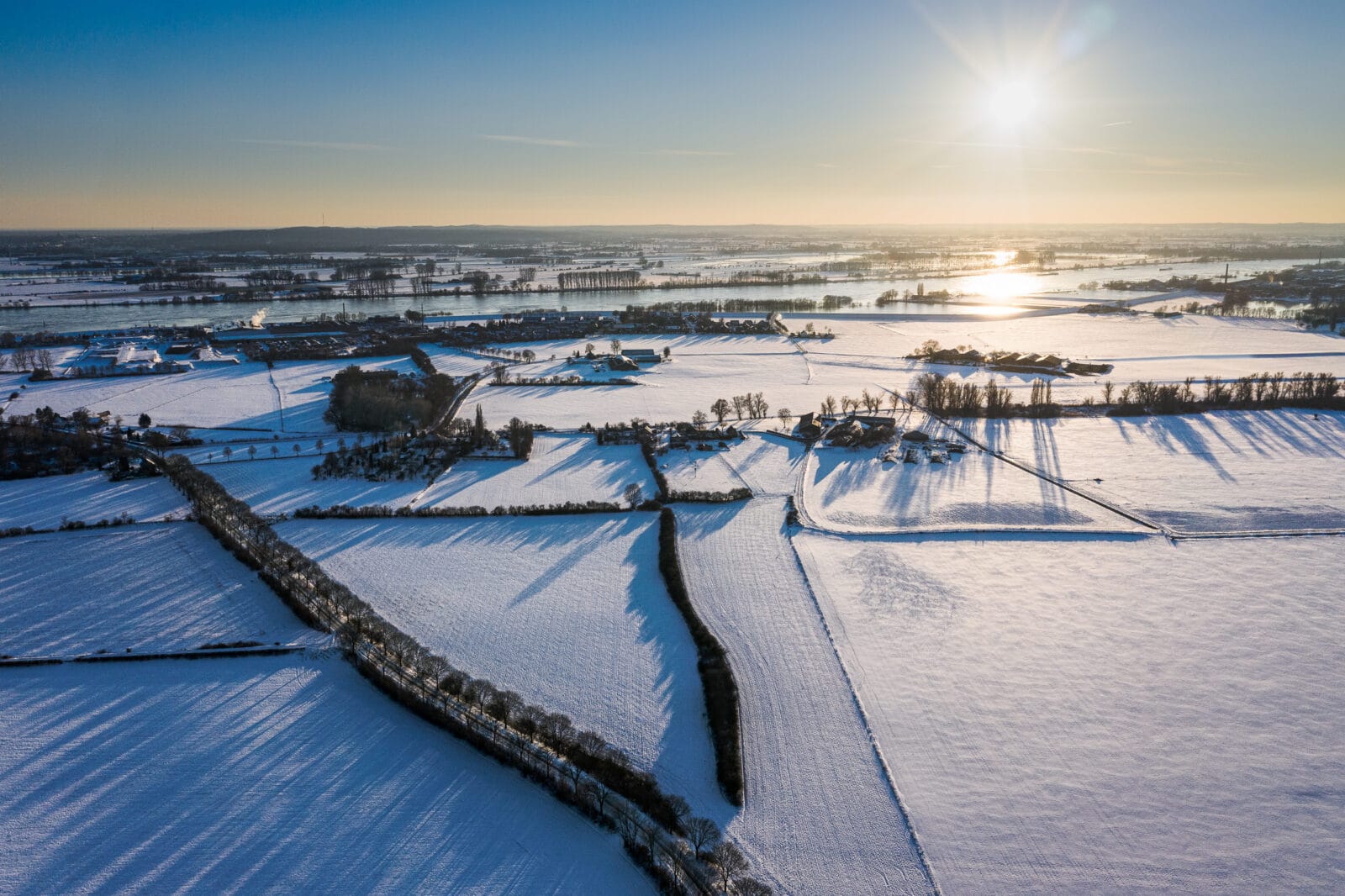 Lange schaduwen over besneeuwde velden bij Elten, van boven