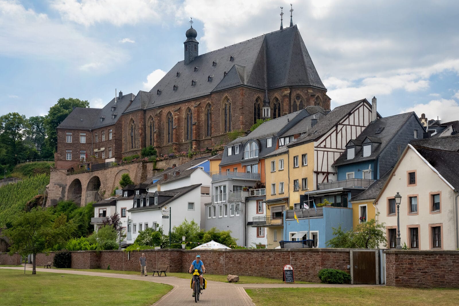 Fietser langs de gekleurde huizen en de kerk van Saarburg