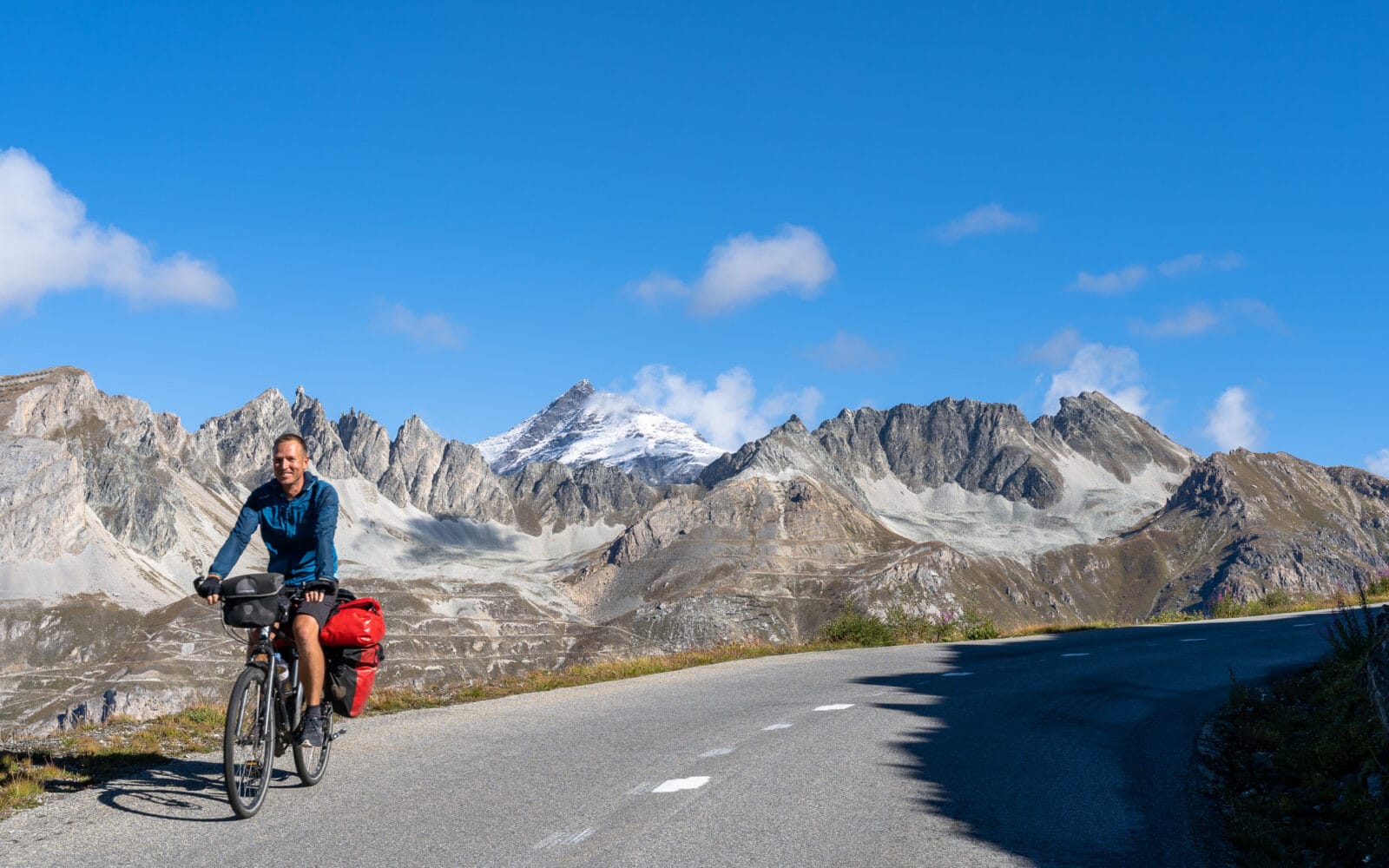 Fietser op de bergweg onder een blauwe hemel bij Val-d'Isère