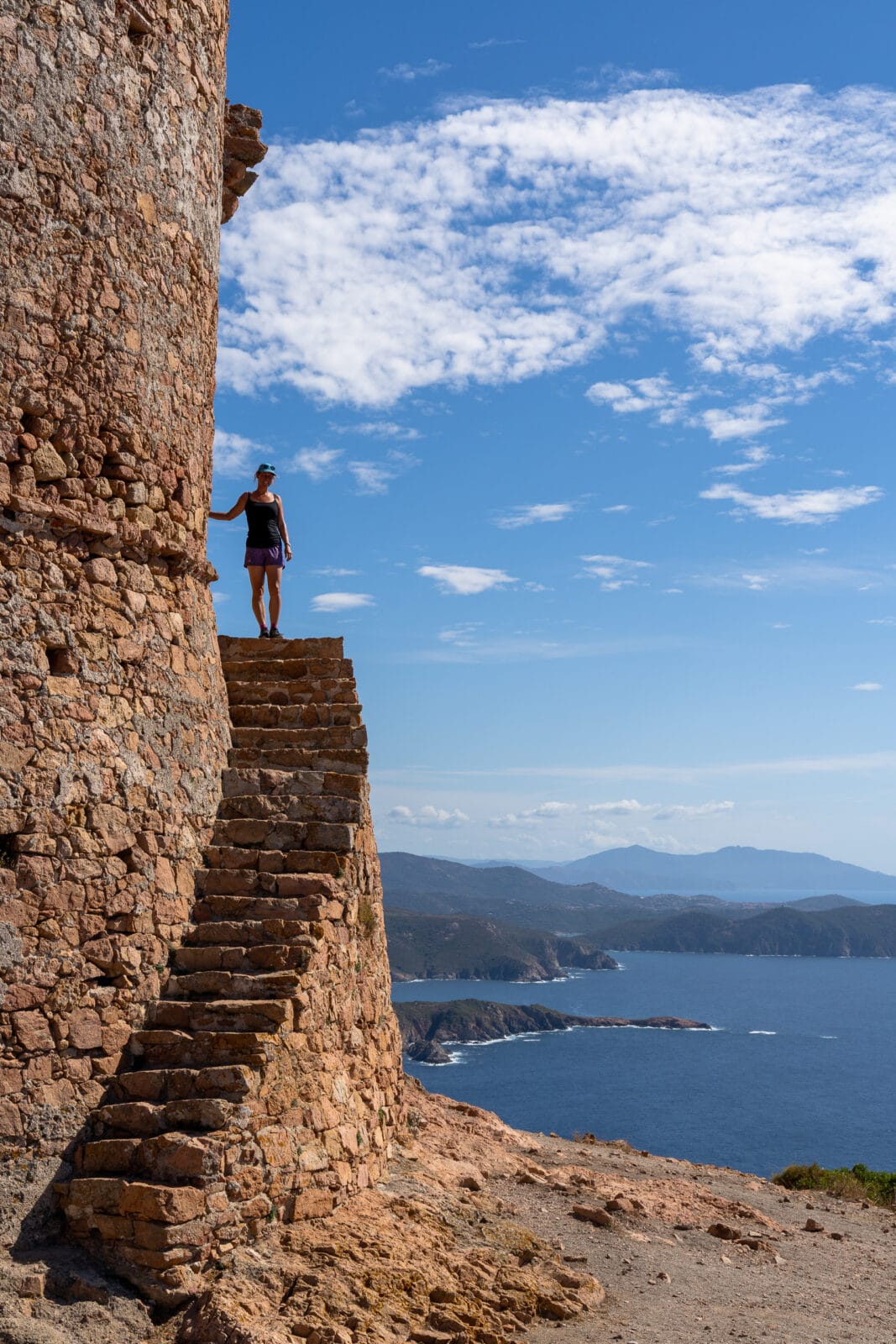 Vrouw op de oude stenen trappen boven zee bij Piana, Corsica