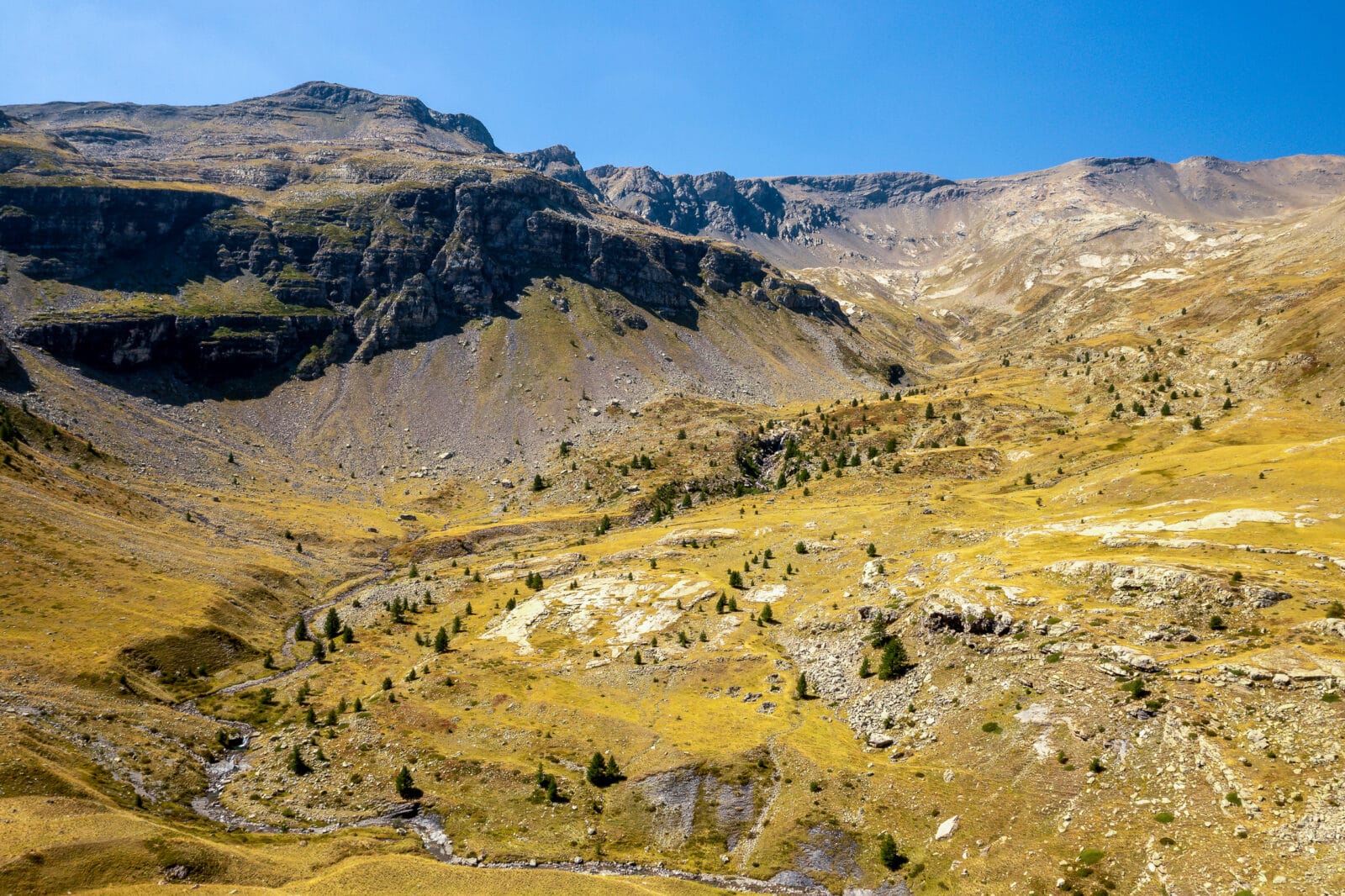 Goudgeel bergdal onder een strakblauwe hemel bij Freissinières, van boven