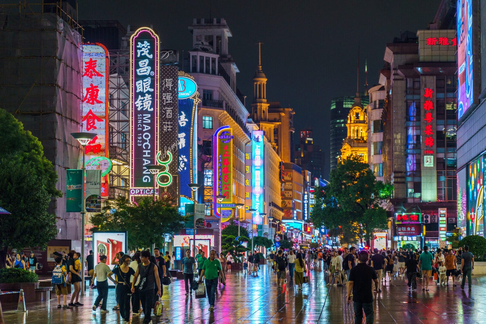 Neonreclames weerspiegeld in het natte wegdek van Nanjing Road, Shanghai