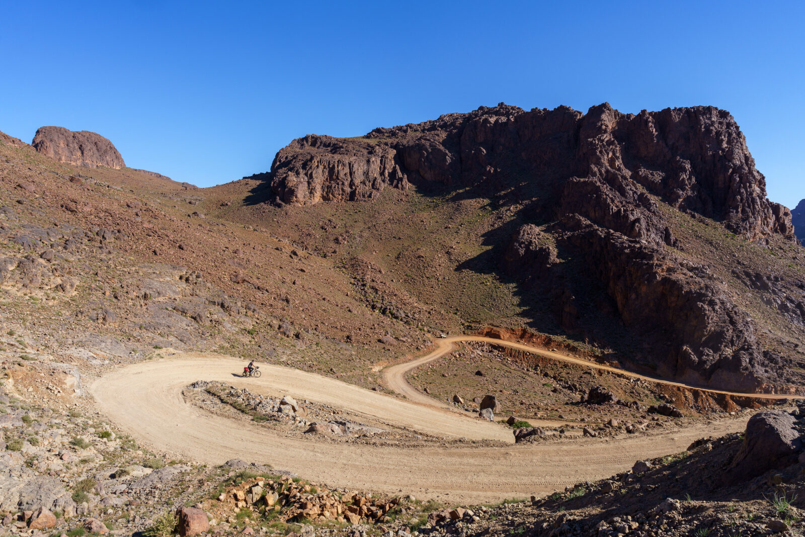 Lone cyclist navigates winding desert mountain road