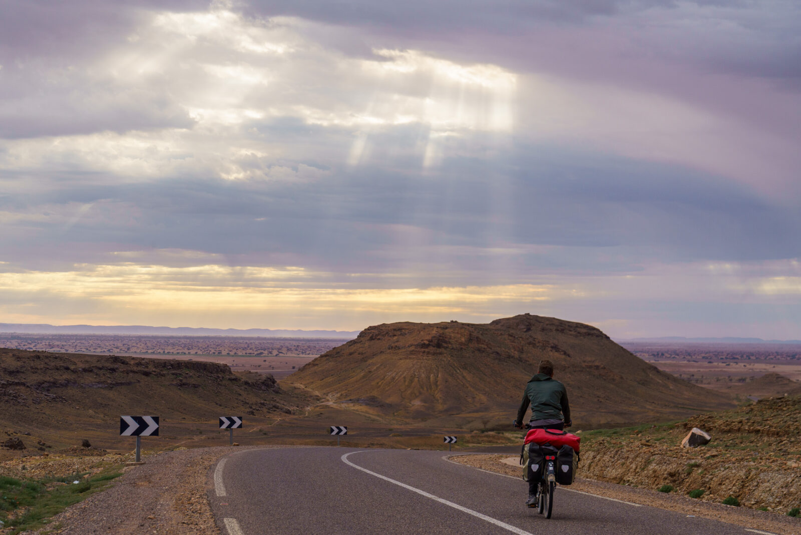 Sunbeams pierce the clouds over a cyclist