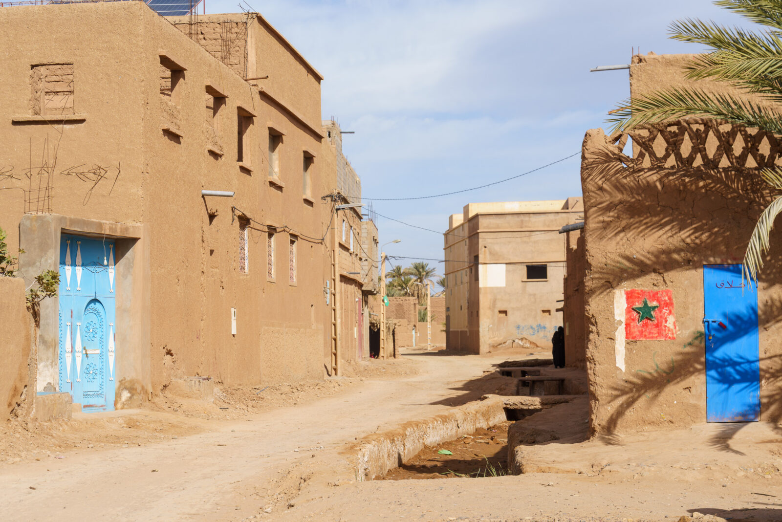 A vibrant blue door stands out in a dusty Moroccan village