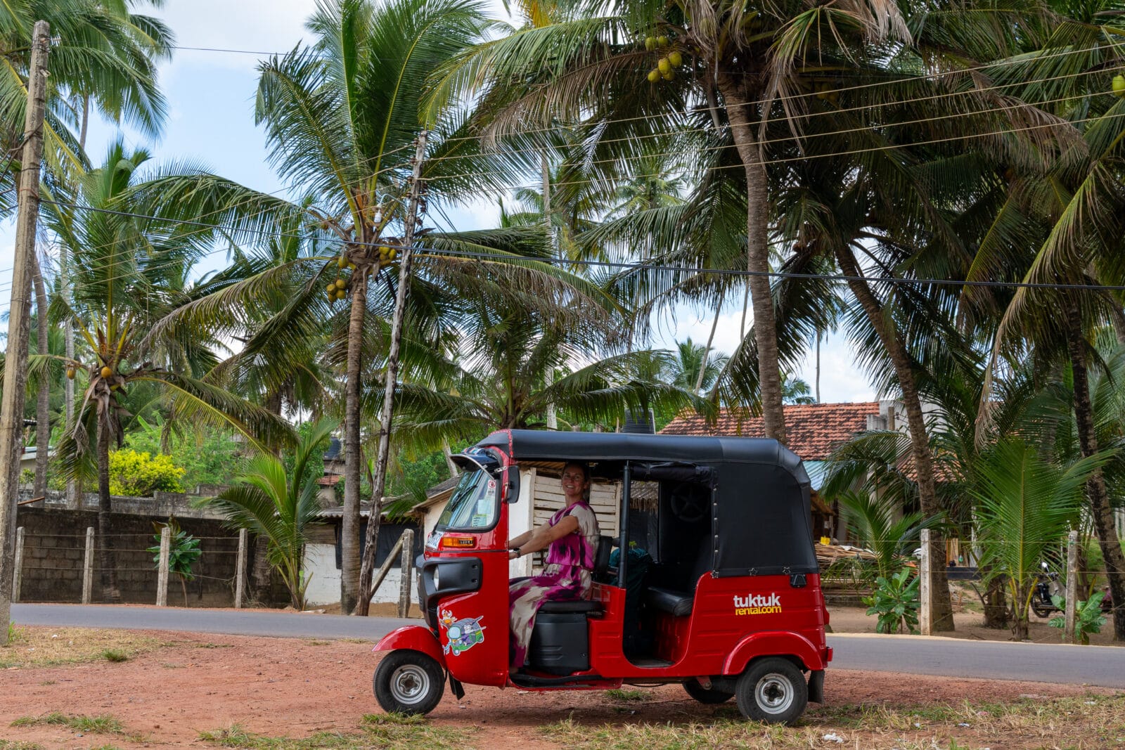 Vrouw in een rode tuktuk onder de palmen bij Katuneriya