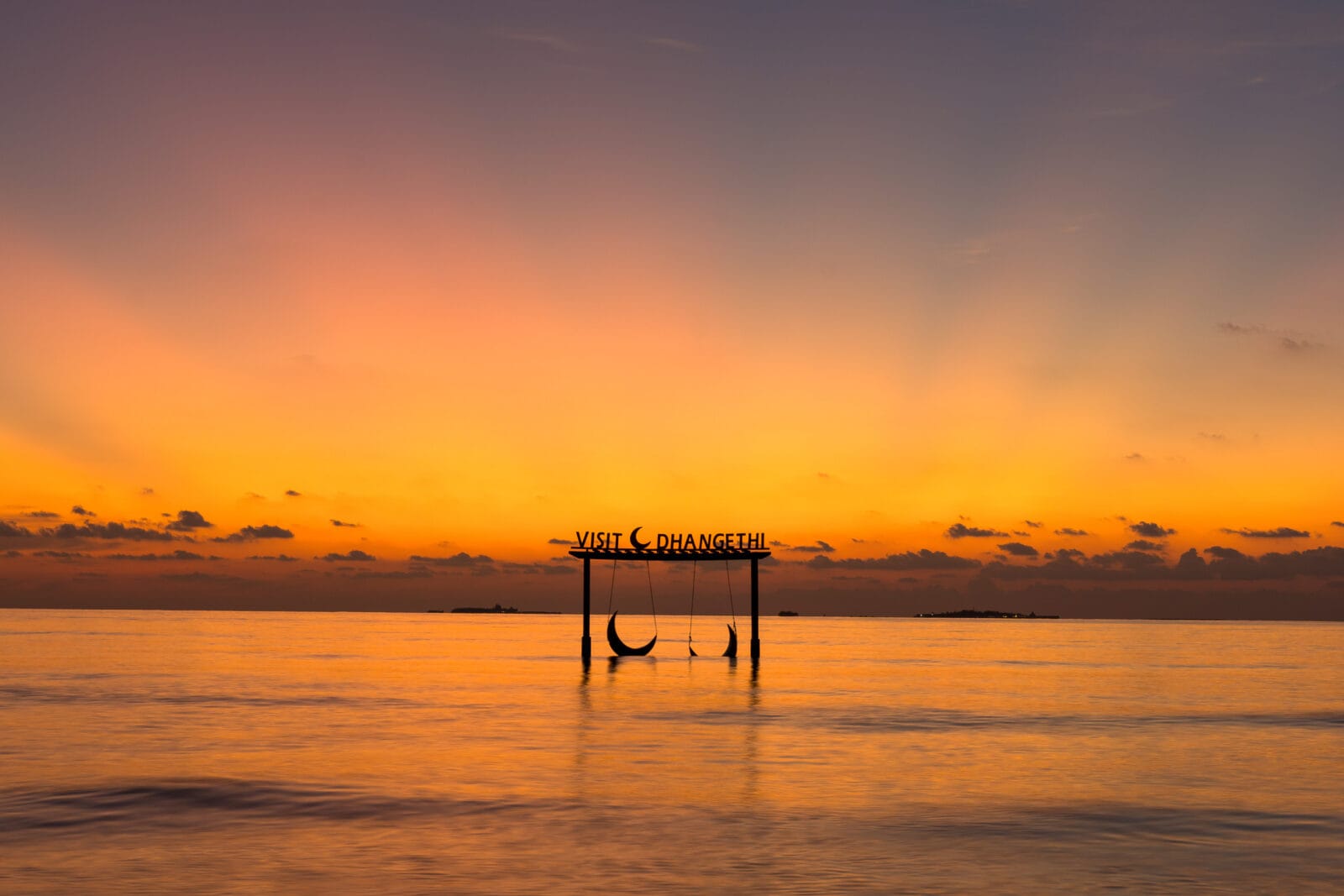 Schommel bij het bord Visit Dhangethi in zee tijdens zonsondergang, Zuid-Ari-atol