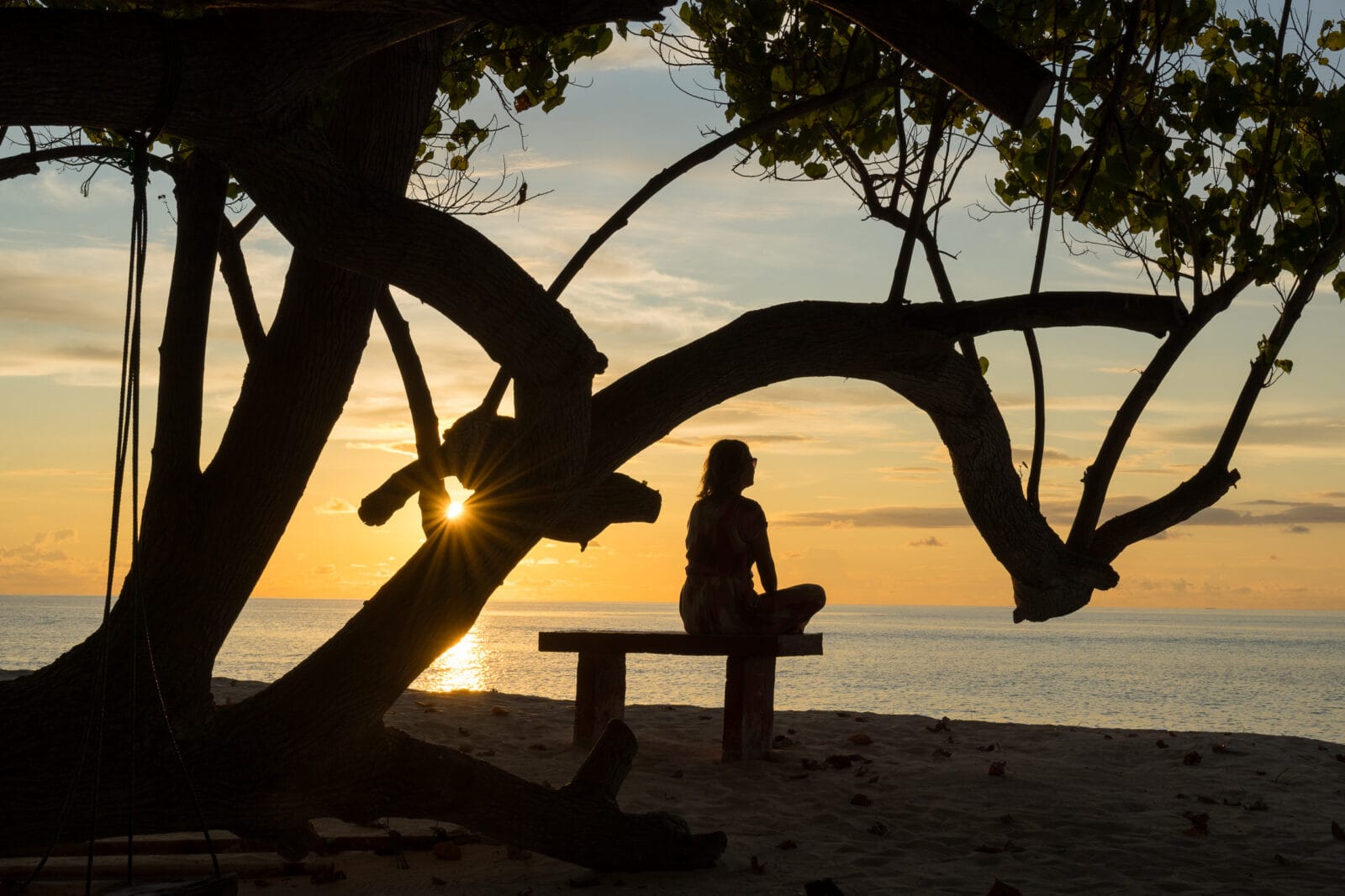 Zonsondergang vanaf een bankje onder een boom op het strand van Dhigurah