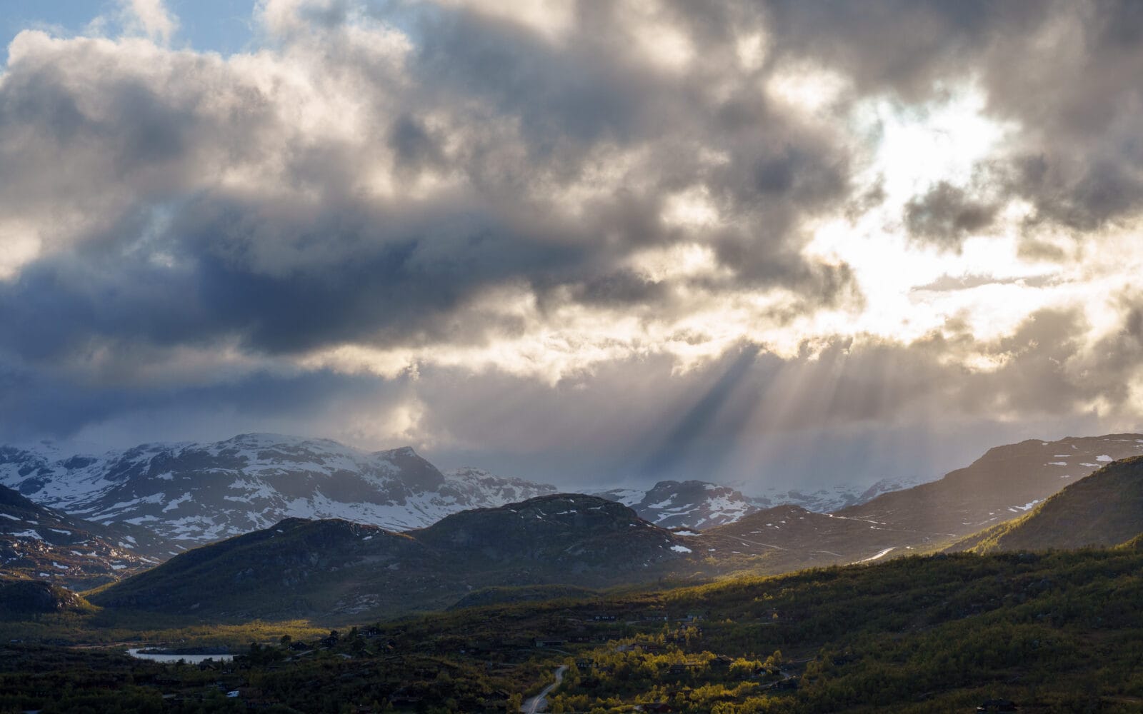 Zonnestralen door de onweerswolken boven de bergen bij Vågsli