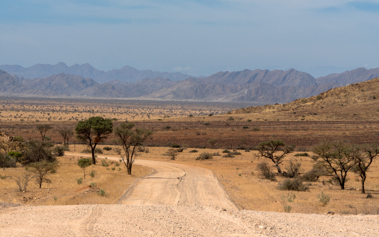 Winding desert road to hazy mountains