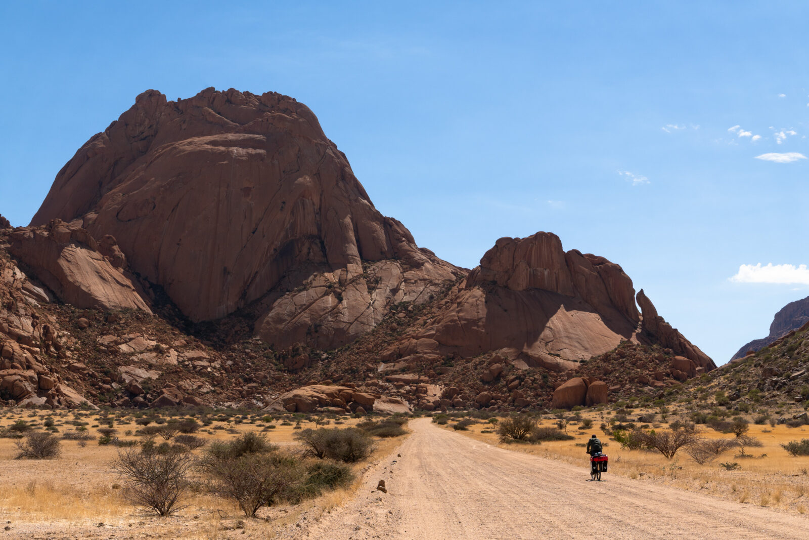 Lone cyclist beneath towering desert mountains