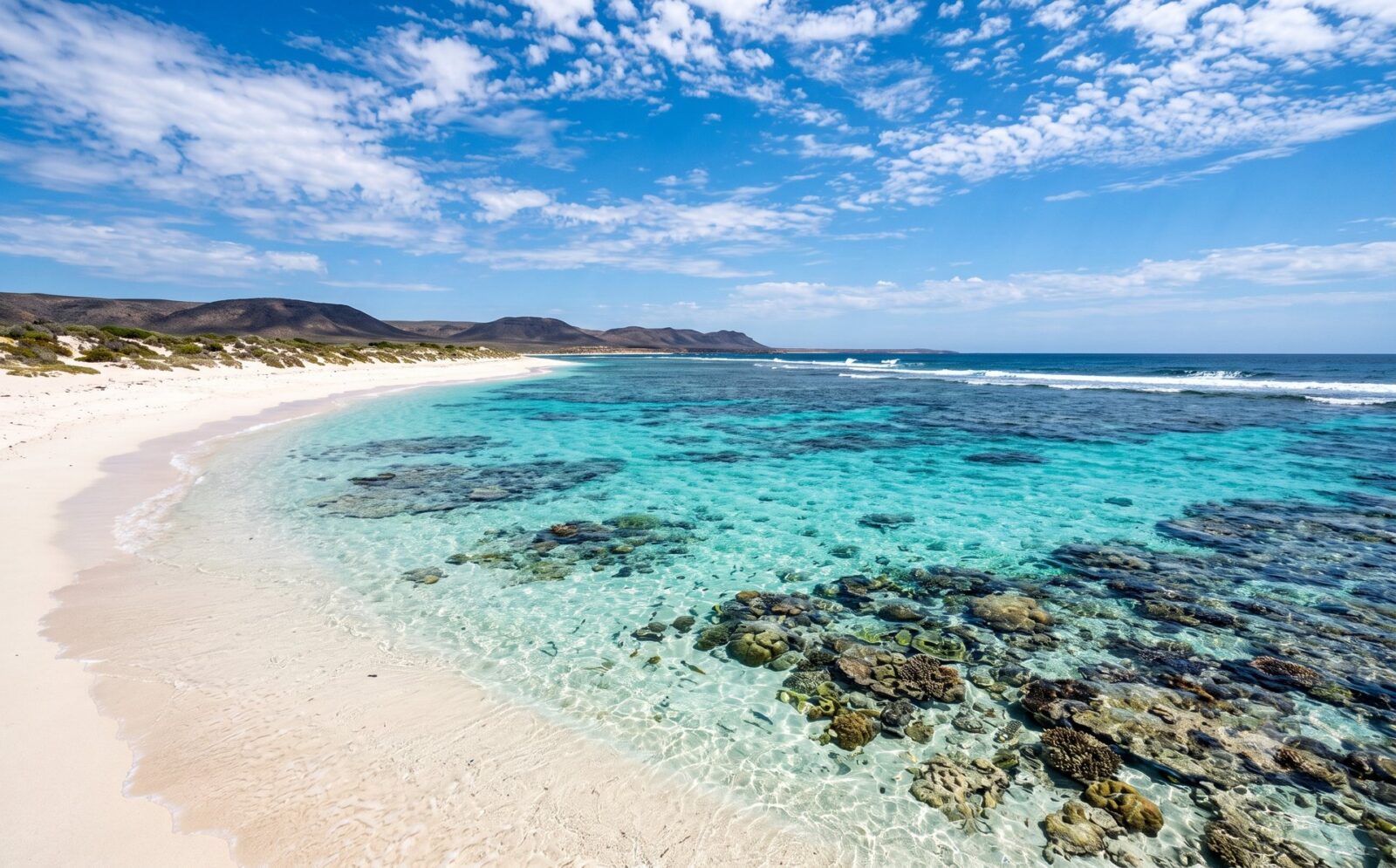Turquoise lagune bij Ningaloo met een koraalrif vlak achter een wit strand en helder ondiep water met zichtbaar koraal