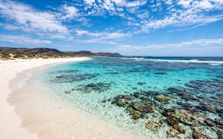 Turquoise lagune bij Ningaloo met een koraalrif vlak achter een wit strand en helder ondiep water met zichtbaar koraal
